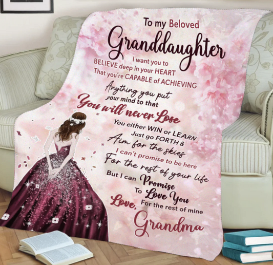 A pink fleece blanket with a heartfelt message printed on it spread out on a couch.