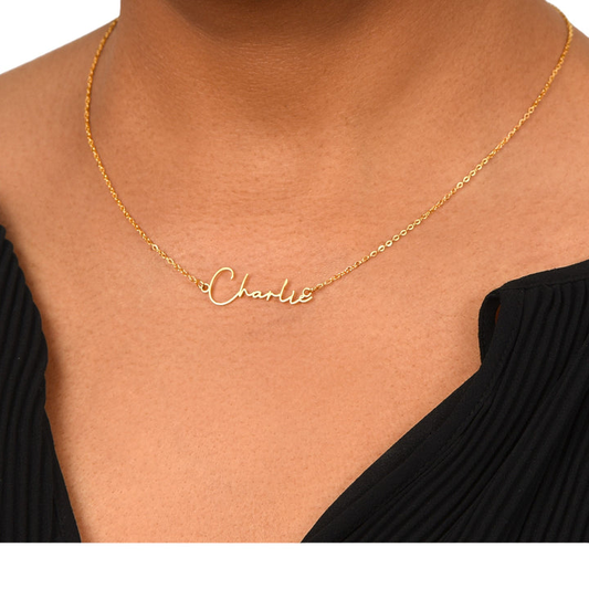 A woman wearing a black shirt with only her neckline shown that has a golden name necklace reading ‘Charlie.’
