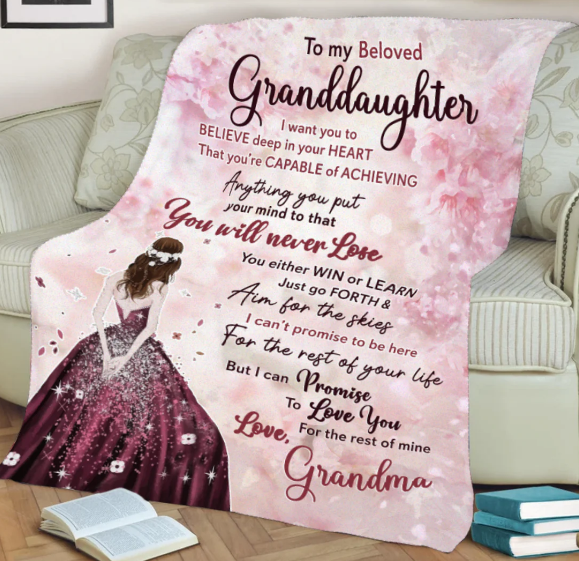  A pink fleece blanket with a heartfelt message printed on it spread out on a couch.